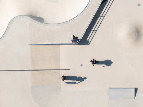 Aerial view of Chiune Sugihara Sakura Park with concrete skate park ramps and bowls and skateboarders casting long shadows Vilnius Vilniaus apskritis Lithuania. Aerial view of Chiune Sugihara Sakura Park with concrete skate park ramps and bowls and skateboarders casting long shadows Vilnius Vilniaus apskritis Lithuania.