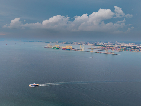 George Town Malaysia 22 September 2026 Aerial view of the Penang ferry sailing across the sea with the industrial port and cranes visible in the background under a cloudy sky.