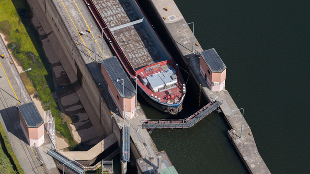 Aerial view of the Rockenau lock on the Neckar River with a cargo ship inside the chamber concrete walls and surrounding water in Eberbach Baden Wurttemberg Germany.
