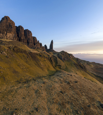 Aerial view of The Storr rock formation and the Old Man of Storr pinnacle rising above the grassy slopes under a soft morning light Isle of Skye Scotland United Kingdom. Aerial view of The Storr rock formation and the Old Man of Storr pinnacle rising above the grassy slopes under a soft morning light Isle of Skye Scotland United Kingdom.