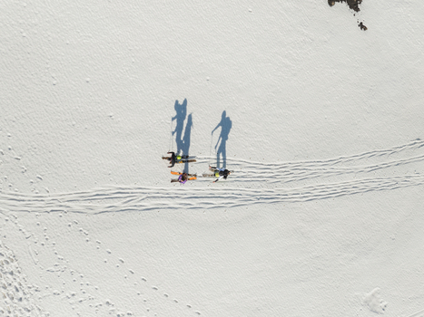 Aerial view of three skiers with long shadows trekking across the snow covered slopes of Mount Etna south side in Nicolosi Sicilia Italy. Aerial view of three skiers with long shadows trekking across the snow covered slopes of Mount Etna south side in Nicolosi Sicilia Italy.