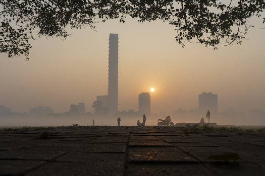 View of a misty morning unveils silhouettes of people and buildings under a pale sun in Kolkata West Bengal India. View of a misty morning unveils silhouettes of people and buildings under a pale sun in Kolkata West Bengal India.