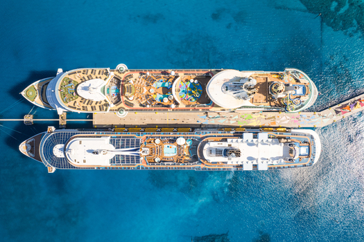 The Bahamas 15 December 2022 Aerial view of two large cruise ships docked at the pier at CocoCay featuring turquoise waters swimming pools and water slides on the decks.