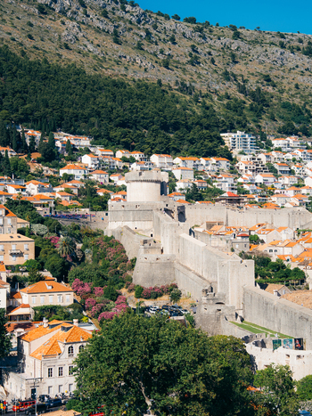 View of the Minceta Tower and historic city walls of the Old Town with orange roofed houses and a rocky mountain backdrop in Dubrovnik Dubrovnik Neretva County Croatia. View of the Minceta Tower and historic city walls of the Old Town with orange roofed houses and a rocky mountain backdrop in Dubrovnik Dubrovnik Neretva County Croatia.