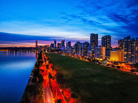 Aerial view of the illuminated Perth skyline at twilight with skyscrapers reflecting over the Swan River adjacent to parkland City of Perth Western Australia Australia.