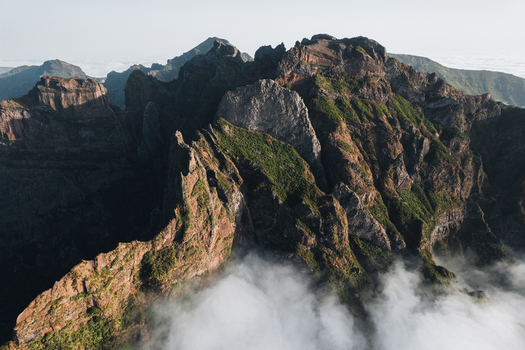 Aerial view of the rugged sun kissed peaks piercing through a sea of ethereal clouds Pico do Areeiro Madeira Portugal.
