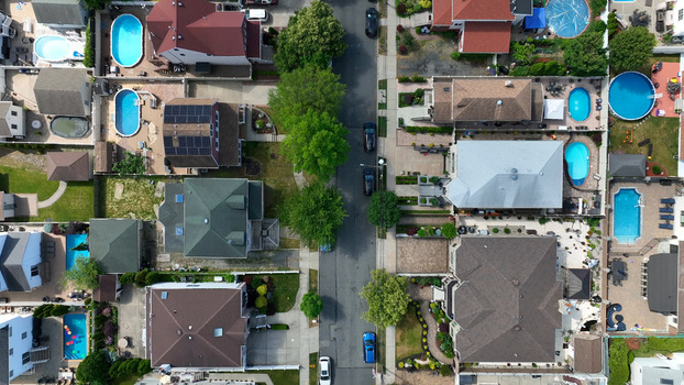 Aerial view of residential houses with swimming pools and lush trees along a suburban street in Tottenville New York New York United States. Aerial view of residential houses with swimming pools and lush trees along a suburban street in Tottenville New York New York United States.