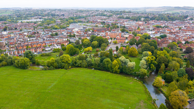 Aerial view of the historic city of Salisbury featuring lush green meadows a winding river and dense urban architecture with red brick buildings. Salisbury Wiltshire United Kingdom. Aerial view of the historic city of Salisbury featuring lush green meadows a winding river and dense urban architecture with red brick buildings. Salisbury Wiltshire United Kingdom.