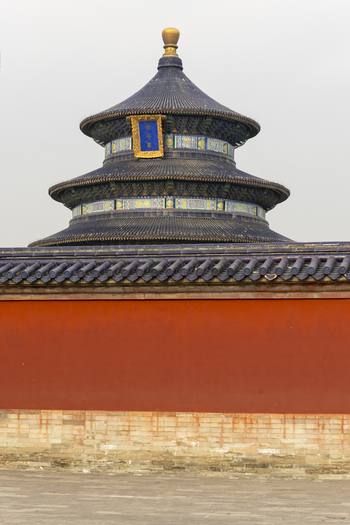 View of the Hall of Prayer for Good Harvests at the Temple of Heaven with its iconic blue tiled roof and golden finial behind a red wall in Beijing Beijing China. View of the Hall of Prayer for Good Harvests at the Temple of Heaven with its iconic blue tiled roof and golden finial behind a red wall in Beijing Beijing China.