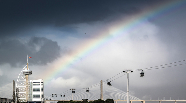 View of a vibrant rainbow arcs across the sky painting a brilliant contrast against the modern architecture and cable cars Lisbon Lisbon Portugal. View of a vibrant rainbow arcs across the sky painting a brilliant contrast against the modern architecture and cable cars Lisbon Lisbon Portugal.