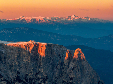 Aerial view of Sciliar peaks kissed by the warm glow of the rising sun contrasting sharply with the cool blues of the Alps mountains Seiser Alm Bolzano South Tyrol Italy.