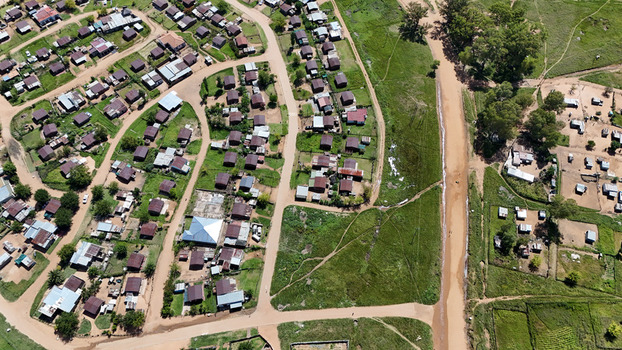 Aerial view of small houses and dirt roads in a rural residential settlement surrounded by green fields and trees Waterberg District Municipality Limpopo South Africa. Aerial view of small houses and dirt roads in a rural residential settlement surrounded by green fields and trees Waterberg District Municipality Limpopo South Africa.
