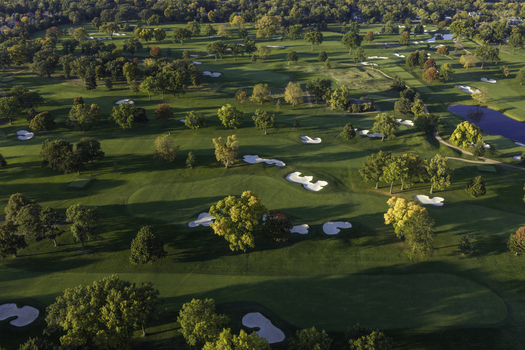 Aerial view of a golf course in autumn with vibrant yellow and orange trees manicured green fairways white sand bunkers and a small pond in Glenview Illinois United States. Aerial view of a golf course in autumn with vibrant yellow and orange trees manicured green fairways white sand bunkers and a small pond in Glenview Illinois United States.