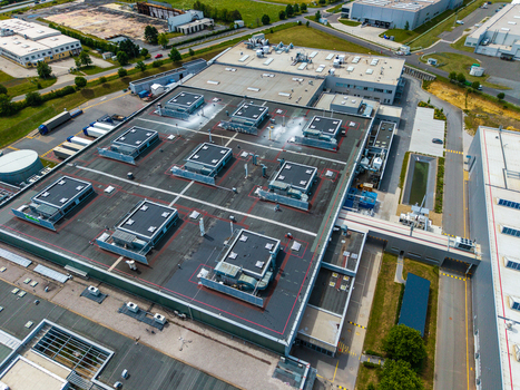 Aerial view of a large industrial warehouse complex with flat rooftops HVAC units and surrounding parking areas in Zebrak Central Bohemian Region Czechia. Aerial view of a large industrial warehouse complex with flat rooftops HVAC units and surrounding parking areas in Zebrak Central Bohemian Region Czechia.