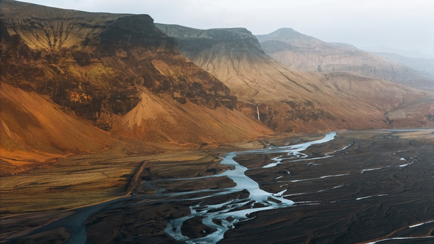 Aerial view of the massive Lomagnupur mountain and a winding braided river flowing through the volcanic landscape in Skaftarhreppur Iceland.