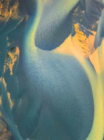 Aerial view of a glacial river delta with intricate patterns of blue water and golden sediment flowing through the landscape in Iceland. Aerial view of a glacial river delta with intricate patterns of blue water and golden sediment flowing through the landscape in Iceland.
