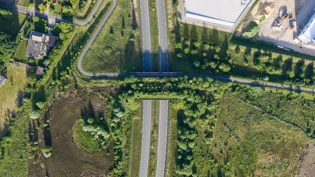 Aerial view of a highway with a green wildlife crossing bridge surrounded by lush vegetation and fields in Venlo Limburg Netherlands. Aerial view of a highway with a green wildlife crossing bridge surrounded by lush vegetation and fields in Venlo Limburg Netherlands.