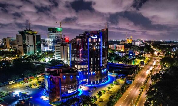 Aerial view of the illuminated Ecobank headquarters building at night surrounded by modern city architecture roads and urban lights in Ghana. Aerial view of the illuminated Ecobank headquarters building at night surrounded by modern city architecture roads and urban lights in Ghana.