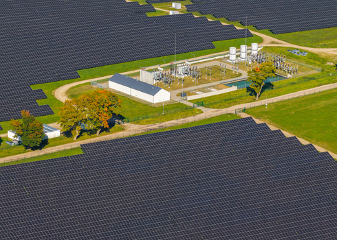 Aerial view of a large solar farm with rows of photovoltaic panels a central electrical substation and green fields in Pomeranian Voivodeship Poland. Aerial view of a large solar farm with rows of photovoltaic panels a central electrical substation and green fields in Pomeranian Voivodeship Poland.