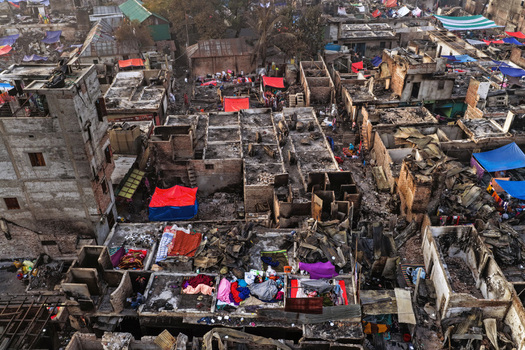 Aerial view of the fire damaged Korail Basti slum with charred structures debris and colorful tarps scattered among dense makeshift housing in Dhaka Dhaka Division Bangladesh.