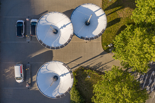 Aerial view of the ENTEGA Charging Station featuring circular solar panels over a parking lot with electric vehicles and green trees in Darmstadt Hessen Germany. Aerial view of the ENTEGA Charging Station featuring circular solar panels over a parking lot with electric vehicles and green trees in Darmstadt Hessen Germany.