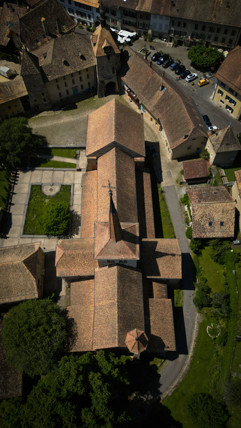 Aerial view of the Romainm&ocirc;tier Abbey with its intricate tiled roofs and the adjacent green courtyard Romainm&ocirc;tier Envy Vaud Switzerland.