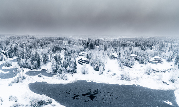Aerial view of a snow covered forest landscape with a frozen lake and scattered houses in Latvia. Aerial view of a snow covered forest landscape with a frozen lake and scattered houses in Latvia.