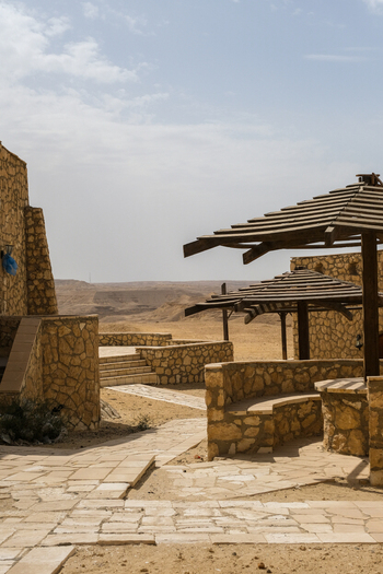 View of arid landscape with stone structures and shaded seating areas under a hazy sky creating a serene desert oasis Cairo Cairo Governorate Egypt. View of arid landscape with stone structures and shaded seating areas under a hazy sky creating a serene desert oasis Cairo Cairo Governorate Egypt.