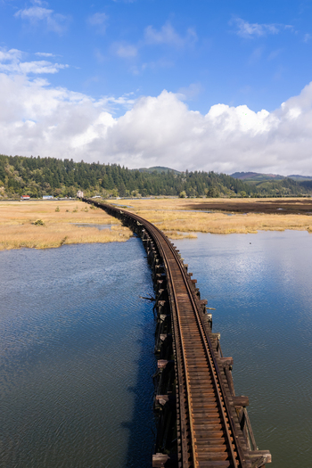 Aerial view of railroad tracks on the Coos Bay Rail Line running across tidal flats near Florence Oregon with open water marsh and coastal backwaters.
