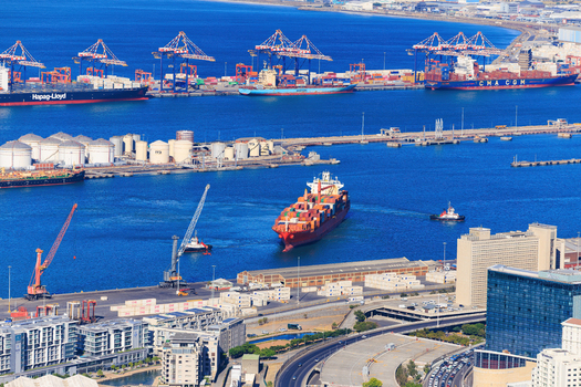 Aerial view of container ships dotting the harbor cranes reaching for the sky contrasting with the city s skyline and the deep blue sea Cape Town Western Cape South Africa.