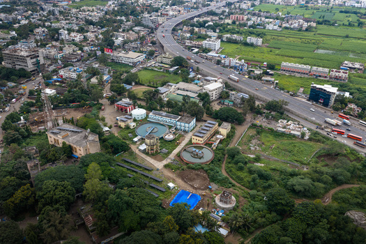 Aerial view of the water treatment plant with circular sedimentation tanks and surrounding green space near a highway in Karad Maharashtra India.