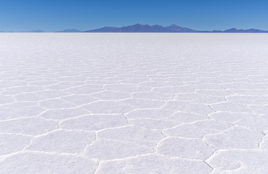 Aerial view of the vast Uyuni Salt Flat with its characteristic hexagonal salt crust patterns under a clear blue sky in Uyuni Potosi Department Bolivia. Aerial view of the vast Uyuni Salt Flat with its characteristic hexagonal salt crust patterns under a clear blue sky in Uyuni Potosi Department Bolivia.