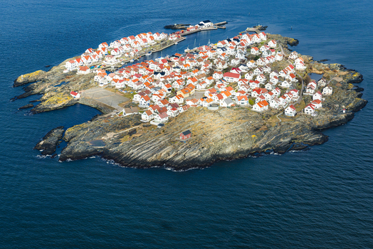 Aerial view of the island of Astol featuring dense clusters of white houses with red roofs surrounded by rocky terrain in Astol Vastra Gotaland County Sweden.