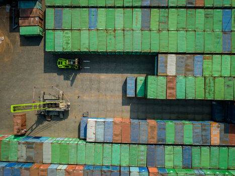Aerial view of a busy shipping container yard with stacks of colorful containers a forklift and a crane in Boyolali Central Java Indonesia.