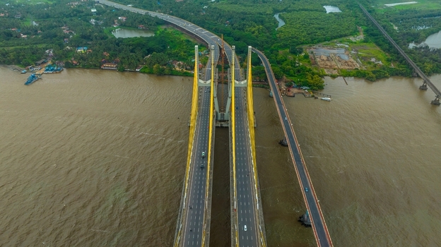 Aerial view of the modern Zuari Bridge spanning the river with cable stayed towers lush green surroundings and traffic flowing on the highway in Cortalim Goa India.