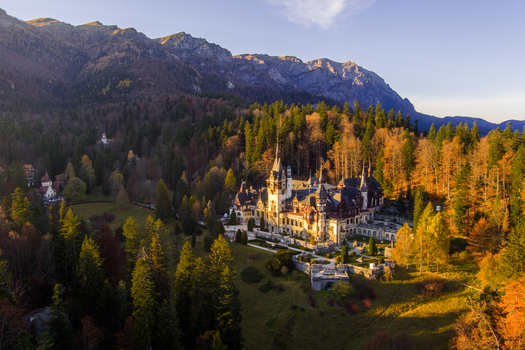 Aerial view of Peles Castle surrounded by dense autumn forests and the Carpathian Mountains in Sinaia Judetul Prahova Romania.
