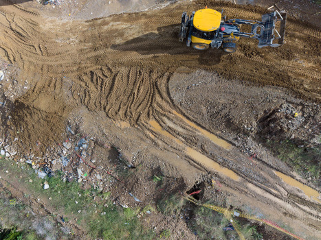 Aerial view of a yellow construction vehicle working on a muddy site with deep tire tracks and earthworks in Istanbul Istanbul Turkiye. Aerial view of a yellow construction vehicle working on a muddy site with deep tire tracks and earthworks in Istanbul Istanbul Turkiye.