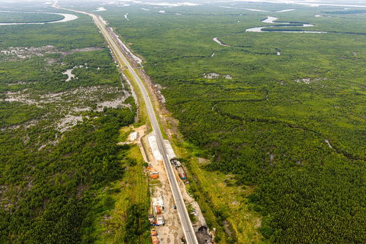 Aerial view of a long straight road cutting through dense green mangrove forests and winding river channels in the Niger Delta region Opobo Town Rivers Nigeria. Aerial view of a long straight road cutting through dense green mangrove forests and winding river channels in the Niger Delta region Opobo Town Rivers Nigeria.