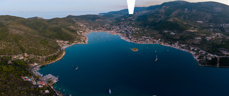 Aerial view of the coastal town of Vathy nestled in a bay on the island of Ithaki with boats in the calm blue water and lush green hills in the background Ithaki Greece.