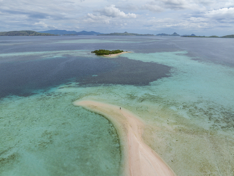 Aerial view of the Flores sandbar surrounded by turquoise water and coral reefs with a small island in the distance East Nusa Tenggara Indonesia.