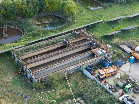 Aerial view of a wastewater treatment plant featuring large sedimentation tanks industrial machinery and a service truck parked on the site in Krakow Lesser Poland Voivode Poland.