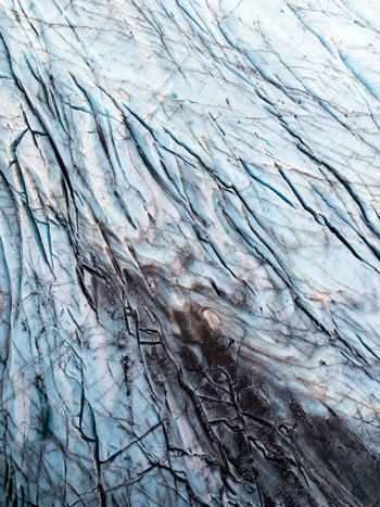 Aerial view of Svinafellsjokull glacier in Iceland showcasing intricate deep blue ice crevasses and dark volcanic ash deposits across the frozen landscape Sveitarfelagid Hornafjordur Iceland. Aerial view of Svinafellsjokull glacier in Iceland showcasing intricate deep blue ice crevasses and dark volcanic ash deposits across the frozen landscape Sveitarfelagid Hornafjordur Iceland.
