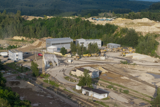 Aerial view of the kopalnia porfiru i diabazu quarry featuring industrial buildings heavy machinery and trucks surrounded by lush forest in Krakow Lesser Poland Voivode Poland. Aerial view of the kopalnia porfiru i diabazu quarry featuring industrial buildings heavy machinery and trucks surrounded by lush forest in Krakow Lesser Poland Voivode Poland.