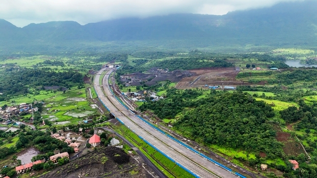 Aerial view of the Delhi Mumbai Expressway winding through the lush green hills and valleys near Badlapur Maharashtra India. Aerial view of the Delhi Mumbai Expressway winding through the lush green hills and valleys near Badlapur Maharashtra India.