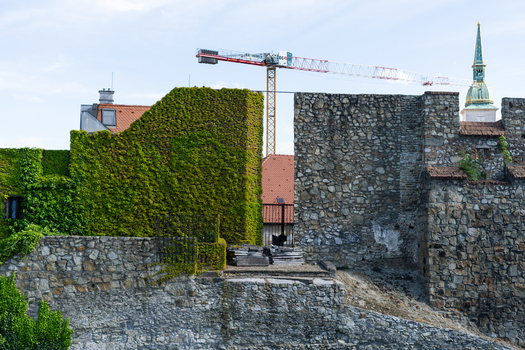 View of the historic stone fortifications and ivy covered walls with St. Martin s Cathedral spire and a construction crane in Bratislava Bratislava Region Slovakia. View of the historic stone fortifications and ivy covered walls with St. Martin s Cathedral spire and a construction crane in Bratislava Bratislava Region Slovakia.