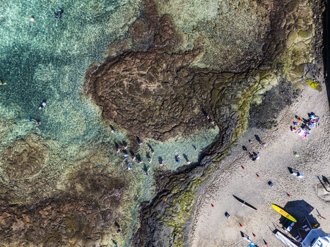 Aerial view of Kahalu u Beach Park with people snorkeling in turquoise water and dark volcanic rock formations along the sandy shore in Kailua Kona Hawaii United States. Aerial view of Kahalu u Beach Park with people snorkeling in turquoise water and dark volcanic rock formations along the sandy shore in Kailua Kona Hawaii United States.