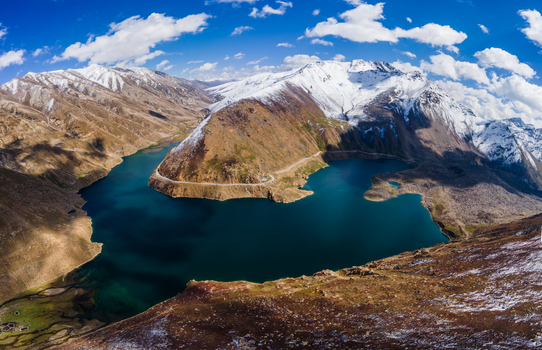 Aerial view of Lulusar Lake with deep blue waters surrounded by snow capped mountain peaks and a winding road in Balakot Khyber Pakhtunkhwa Pakistan. Aerial view of Lulusar Lake with deep blue waters surrounded by snow capped mountain peaks and a winding road in Balakot Khyber Pakhtunkhwa Pakistan.
