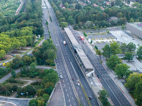 Aerial view of the historic AVUS Tribune grandstand situated along the multi lane AVUS motorway surrounded by lush trees and urban infrastructure in Berlin Berlin Germany. Aerial view of the historic AVUS Tribune grandstand situated along the multi lane AVUS motorway surrounded by lush trees and urban infrastructure in Berlin Berlin Germany.
