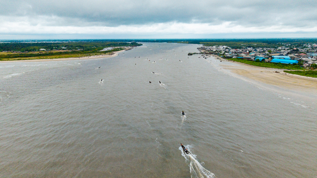 Aerial view of Ibeno Beach at the Kwa Ibo River estuary with small fishing boats navigating the water sandy shores and coastal settlement in Kwa Ibo Akwa Ibom Nigeria.