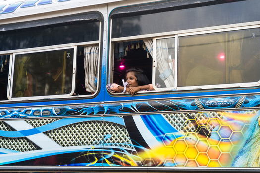Sri Lanka 22 February 2026 View of a young girl looking out of a colorful bus window while resting her chin on her hand.